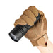 A hand wearing brown tactical gloves holds the Acebeam X20 flashlight, angled forward.