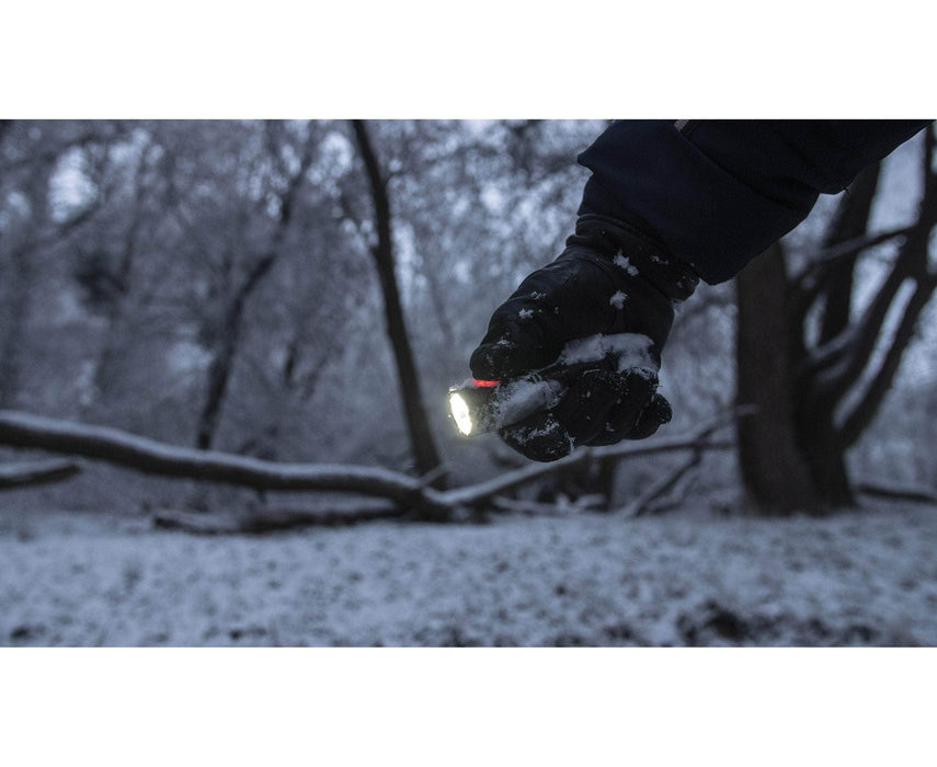 A person wearing a glove holds an Armytek Partner C2 Magnet USB - Warm flashlight in a snowy forest.