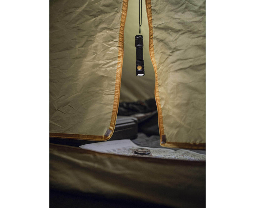 An Armytek Partner C2 Magnet USB - White flashlight hangs from the roof of an open tent, illuminating a map and backpack inside.