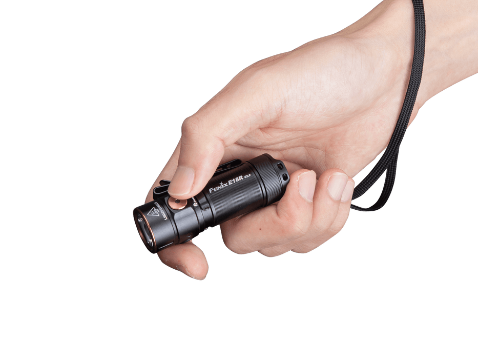 A hand holds the Fenix E18R V2, a sleek rechargeable LED flashlight with a strap, set against a plain black background. Ideal as an everyday carry (EDC) accessory, this compact tool shines with an impressive 1200 lumens.