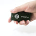 A hand is holding a small, rectangular, green device labeled "Manker F14 Flighter Dual Beam Multi-Purpose EDC Flashlight" with a circular button and a triangle symbol on the front, functioning as both an EDC flashlight and powerbank.