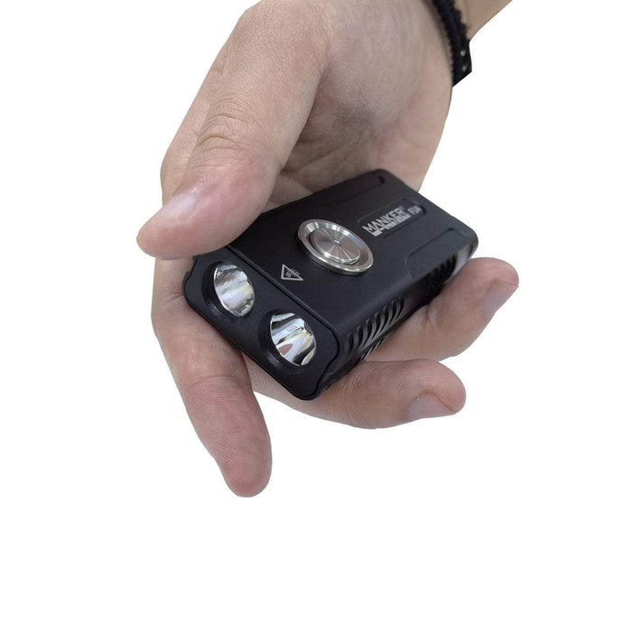 A hand holding a compact black EDC flashlight with dual beams and a central button, showcasing the brand "Manker F14 Flighter Dual Beam Multi-Purpose EDC Flashlight.