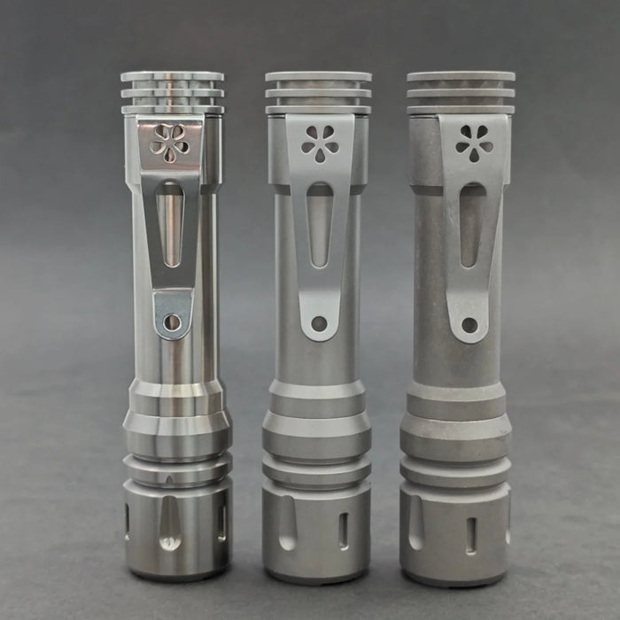 Three ReyLight LANapple - Ti flashlight bodies in silver and grey tones, standing upright on a grey surface.