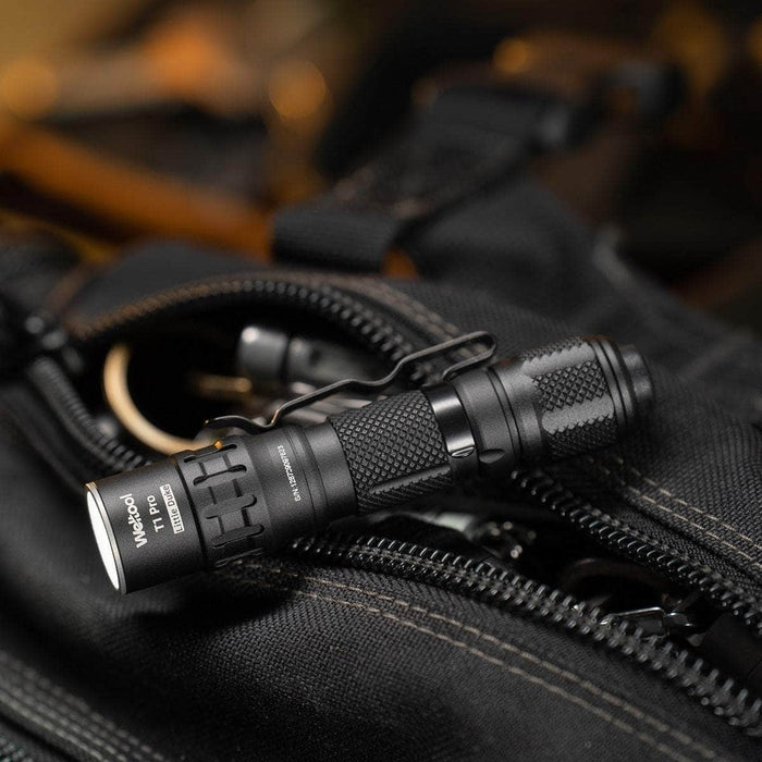 Close-up of the Weltool T1 Pro V2 black tactical flashlight, perfect for everyday carry, placed on a black zippered bag with textured fabric and visible straps.