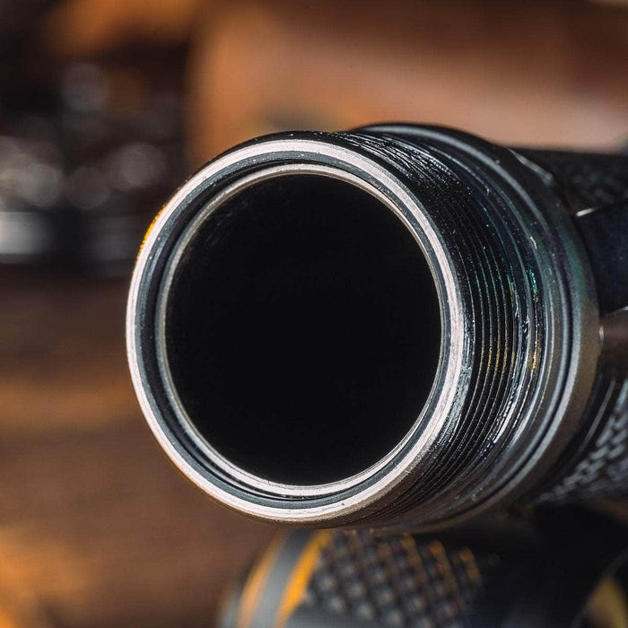 Close-up view of the threaded metallic opening of a Weltool T12 Plus tactical flashlight, designed to fit a 21700 battery, situated on a wooden surface.