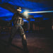 In a dimly lit space, a tactical officer in gear aims a Weltool W3Pro TAC Mini equipped with an LEP light source.